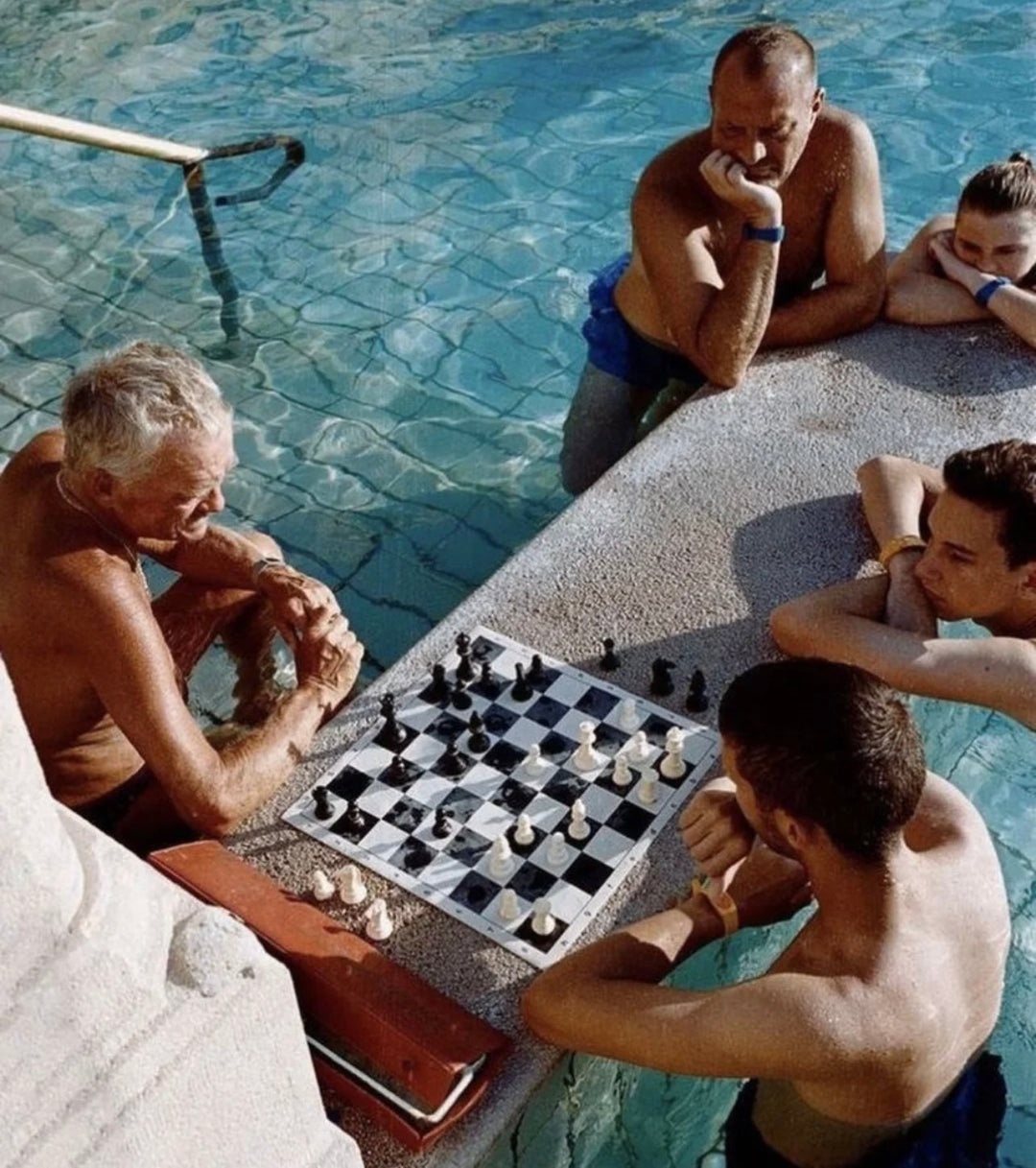 Men playing chess poolside – symbolizing silver vs stainless steel jewelry debate