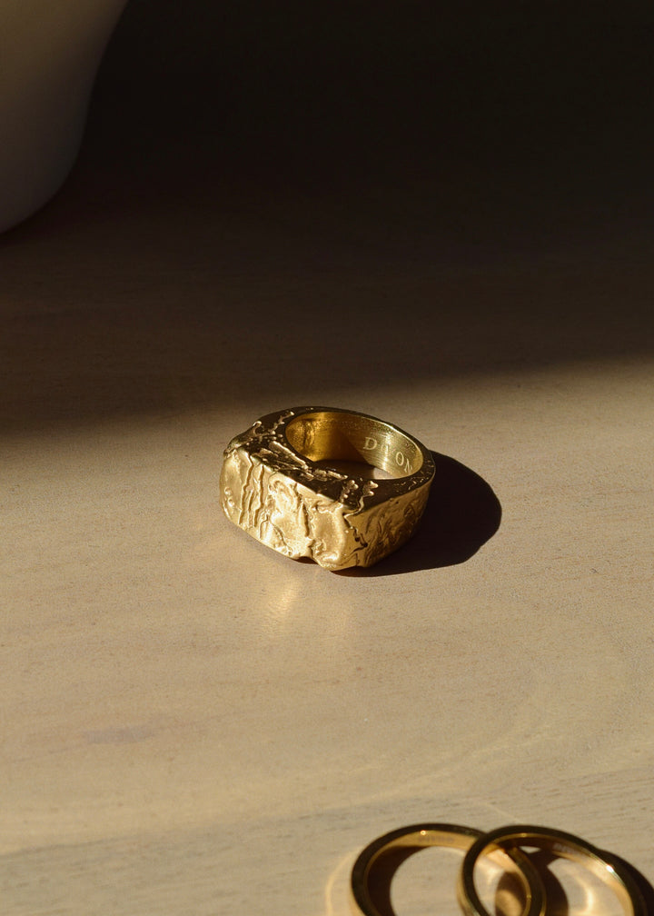 Handcrafted unisex cracked gold ring by Divon Jewelry, 18K gold-plated over stainless steel, displayed on a wooden surface with soft lighting.