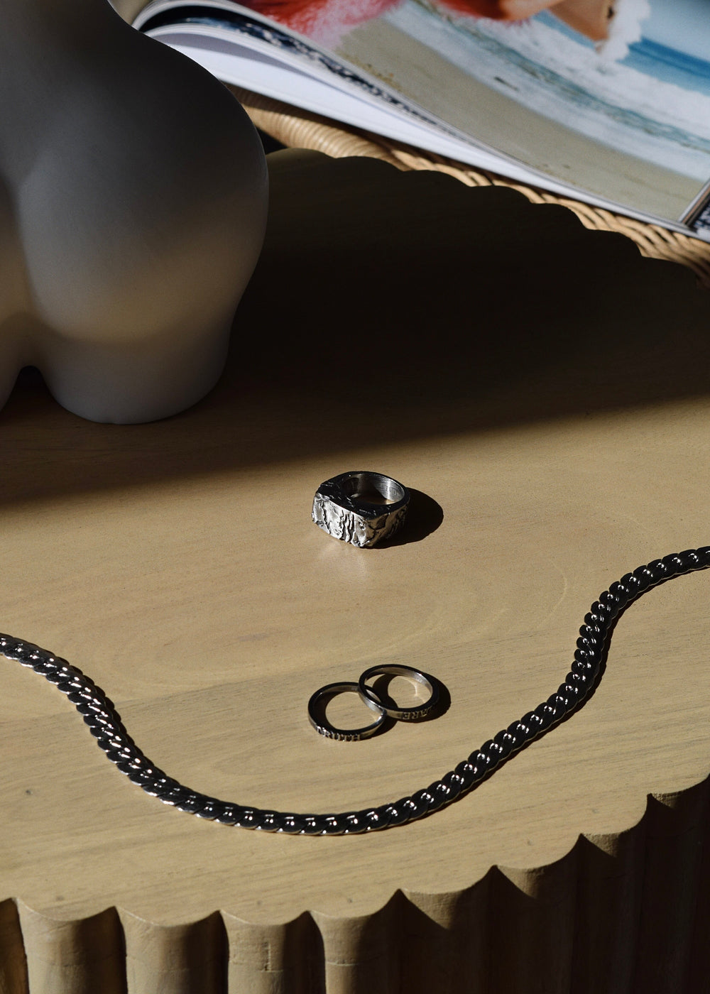 A silver DIVON ring sits on top of a wooden table.